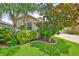 Lush front yard featuring vibrant landscaping, palm trees and fresh green grass at 2450 Dovesong Trace Dr, Ruskin, FL 33570