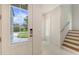 Bright entryway showcases modern stairs and a view to the outside with a beautiful, landscaped front yard and blue sky at 2596 Floyd St, Sarasota, FL 34239