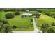 Expansive aerial view of a beautiful white home on lush green property with pond, barn, and surrounding mature trees at 3100 Lena Ln, Sarasota, FL 34240