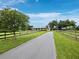 Long paved driveway leads to a beautiful white home, accented by mature trees and wooden fences at 3100 Lena Ln, Sarasota, FL 34240