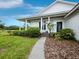 Well-maintained white home with a covered porch, manicured lawn, and a lush garden, set on a large property at 3100 Lena Ln, Sarasota, FL 34240
