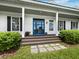 Close-up of the front of the house featuring a beautiful blue front door, charming shutters, and landscaped bushes at 3100 Lena Ln, Sarasota, FL 34240