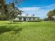 Beautiful white home with metal roof, blue front door, manicured lawn and mature trees offer the home great curb appeal at 3100 Lena Ln, Sarasota, FL 34240