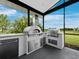An outdoor kitchen with stainless steel pizza oven and grill overlooks an expansive green lawn at 3100 Lena Ln, Sarasota, FL 34240
