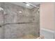 Bathroom shower with marble-look tile, glass door, a shower head, a mounted seat, and grab bars at 327 40Th W Ct, Palmetto, FL 34221