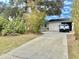 Exterior view of a one-story home with a long driveway and well-manicured lawn and some trees at 3767 Pinstar Ter, North Port, FL 34287