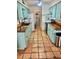 Well-lit kitchen with terracotta tile flooring, wood counters, and turquoise cabinets and stainless appliances at 3767 Pinstar Ter, North Port, FL 34287
