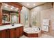 Elegant bathroom featuring a jacuzzi tub, a walk-in shower, and luxurious vanity with decorative lighting at 3906 Twin Rivers Trl, Parrish, FL 34219