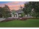 Charming two-story home featuring a lush green lawn and mature trees under an orange sunset at 3906 Twin Rivers Trl, Parrish, FL 34219