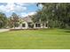 Charming two-story home featuring a lush green lawn and mature trees against a cloudy blue sky at 3906 Twin Rivers Trl, Parrish, FL 34219
