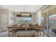Cozy dining room with seating for six, modern lighting, and sliding glass door access to the balcony at 4267 Expedition Way, Osprey, FL 34229