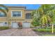 Inviting two-story townhome featuring attached garages, red brick driveway, and lush tropical landscaping at 4267 Expedition Way, Osprey, FL 34229
