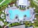 Overhead view of a resort-style pool with umbrellas, palm trees, and ample seating, surrounded by lush landscaping at 4704 Sarca Ct, Lakewood Ranch, FL 34211