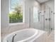 Bright bathroom features a modern soaking tub, large window, and glass-enclosed shower at 4704 Sarca Ct, Lakewood Ranch, FL 34211