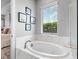 Bright bathroom features a modern soaking tub, large window, and tile flooring with views to the backyard at 4704 Sarca Ct, Lakewood Ranch, FL 34211