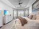 Sunlit primary bedroom features tray ceiling, wood accent wall, and beachy decor for a peaceful space at 4704 Sarca Ct, Lakewood Ranch, FL 34211