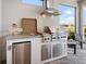 Outdoor kitchen with stainless steel grill, sink, and mini fridge overlooking a lake at 4704 Sarca Ct, Lakewood Ranch, FL 34211