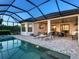 Luxurious screened-in pool area with lounge chairs, an outdoor kitchen, and views of the backyard and open sky at 4704 Sarca Ct, Lakewood Ranch, FL 34211