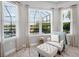 Bright sitting area with white chair, ottoman, and three windows providing natural light and green outdoor views at 4704 Sarca Ct, Lakewood Ranch, FL 34211