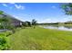 Expansive backyard overlooks a serene lake with lush landscaping and mature trees at 4735 Cassio Ct, Bradenton, FL 34211