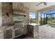 This is an outdoor kitchen with stone counter tops, stainless steel appliances, a grill, and a vent hood for outdoor cooking at 4735 Cassio Ct, Bradenton, FL 34211
