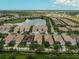 An aerial view shows a well-planned community featuring tiled-roof homes and a serene lake reflecting the clear blue sky at 5662 Fossano Dr, Sarasota, FL 34238