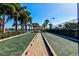 A scenic view shows two well-maintained bocce courts, bordered by palm trees, with a peaceful lake in the background at 5662 Fossano Dr, Sarasota, FL 34238