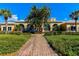 A clubhouse surrounded by lush greenery, showcasing expansive windows and a brick walkway, creates an inviting gathering space at 5662 Fossano Dr, Sarasota, FL 34238