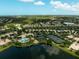 Aerial view of a community showcasing a clubhouse, pool, tennis courts, and a lake reflecting a vibrant blue sky at 5662 Fossano Dr, Sarasota, FL 34238