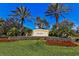 Landscaped community entrance sign with vibrant flowers, mature palms, and manicured lawn at 5662 Fossano Dr, Sarasota, FL 34238