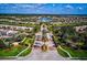 A stunning aerial view showcases a community entrance featuring manicured lawns, palm trees, and a scenic lake backdrop at 5662 Fossano Dr, Sarasota, FL 34238