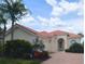 Charming single-story home with a red tile roof, brick driveway, arched entryway, and well-maintained landscaping at 5779 Wilena Pl, Sarasota, FL 34238