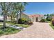 Well-maintained home featuring lush landscaping, mature trees, and a classic tile roof, with brick paver driveway at 5779 Wilena Pl, Sarasota, FL 34238