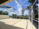 Spacious screened lanai with views of the lush backyard landscaping, blue sky, and the lake at 5779 Wilena Pl, Sarasota, FL 34238