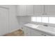 Laundry area offering white cabinets, a sink, and a tiled backsplash with natural light at 5779 Wilena Pl, Sarasota, FL 34238