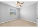 Bright bedroom featuring plush carpet, a ceiling fan, and a sunny window with blinds at 6550 Devesta Loop, Palmetto, FL 34221