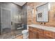 Rustic style bathroom with wood vanity, mosaic tile, large mirror, and glass enclosed shower at 676 Regatta Way, Bradenton, FL 34208