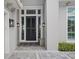 Elegant front entrance with black door, stylish lanterns, and textured stone bench at 676 Regatta Way, Bradenton, FL 34208