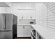 Pantry with stainless steel refrigerator, white cabinets, and a white tile backsplash at 676 Regatta Way, Bradenton, FL 34208