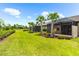 Expansive backyard featuring lush lawns, palm trees, manicured landscaping, a serene pond, and a screened patio at 7661 Summerland Cv, Bradenton, FL 34202