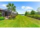 Expansive backyard showing a manicured lawn, beautiful landscaping, mature palm trees, and a serene pond view at 7661 Summerland Cv, Bradenton, FL 34202