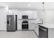 Modern kitchen featuring stainless steel appliances, white cabinets and countertops, and tile flooring at 7661 Summerland Cv, Bradenton, FL 34202