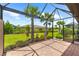 Screened in patio offers brick floors, exterior views of manicured green grass, palm trees and well-maintained landscaping at 7661 Summerland Cv, Bradenton, FL 34202