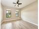 A bright bedroom features two windows, wood tile floors, and a ceiling fan at 7781 Grande Shores Dr, Sarasota, FL 34240