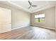 A serene bedroom with wood tile floors, a ceiling fan, and natural light from a window at 7781 Grande Shores Dr, Sarasota, FL 34240