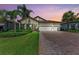 Beautiful single-story home featuring a three-car garage, lush landscaping, and a brick paver driveway at 7781 Grande Shores Dr, Sarasota, FL 34240