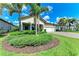 Charming home with a manicured lawn, lush landscaping, and a paved driveway leading to a two-car garage at 7781 Grande Shores Dr, Sarasota, FL 34240