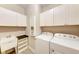 Laundry room featuring a sink, white cabinets, modern washer, and a dryer at 7781 Grande Shores Dr, Sarasota, FL 34240
