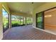 A covered brick patio leading to a manicured backyard with views and sliding glass doors at 7781 Grande Shores Dr, Sarasota, FL 34240