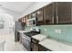Well-lit kitchen featuring stainless steel appliances and dark cabinets with a light backsplash at 8261 Miramar Way # 8261, Lakewood Ranch, FL 34202